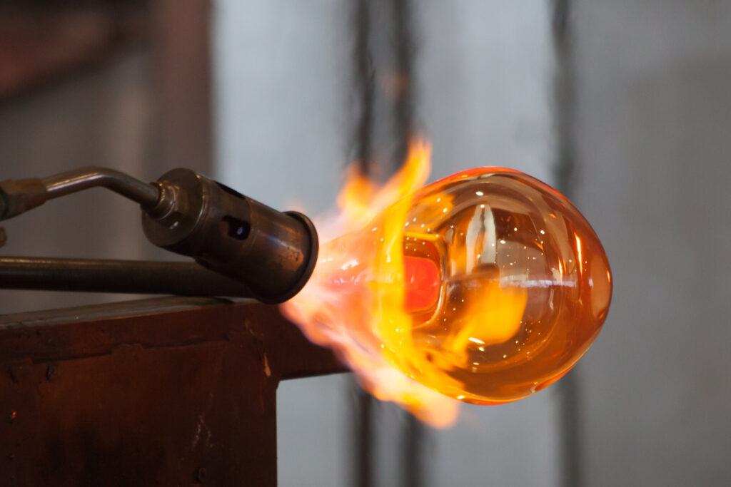 a glass blower forming a pipe under a blowtorch
