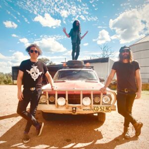 A picture of the band Super American Eagle with a car